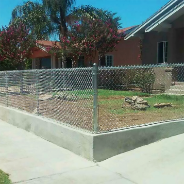 A chain link fence stands in front of a residential house, providing a clear boundary around the property.