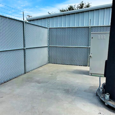 A large storage building enclosed by a fence, featuring a prominent door for access.