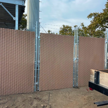 A construction worker builds a wooden fence around a newly constructed building, ensuring safety and security for the site.