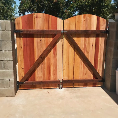 Two wooden gates flanked by a wooden fence, creating an inviting entrance to a garden or property.