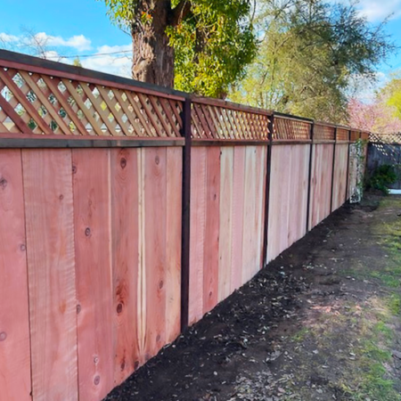 A wooden fence featuring lattice designs at both the top and bottom sections, enhancing its decorative appeal.