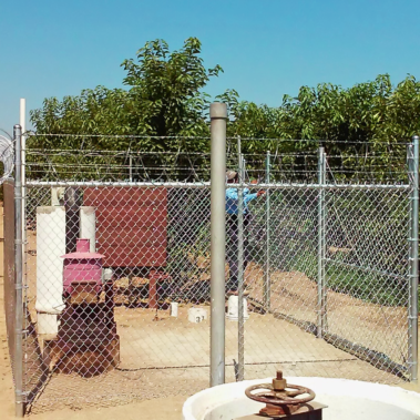 A fenced area with a gate surrounds a prominent water tank, highlighting a peaceful outdoor environment.