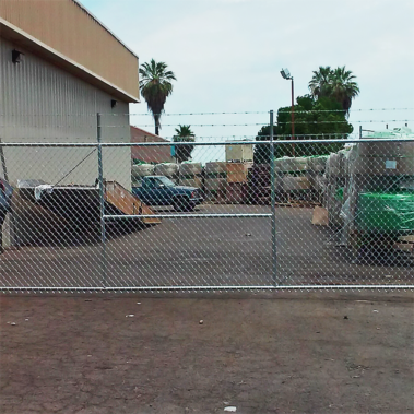 A chain link fence featuring a gate is positioned in front of a building, serving as a barrier and entry point.