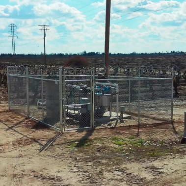 A fence enclosing a space with a water pump with a gate for access