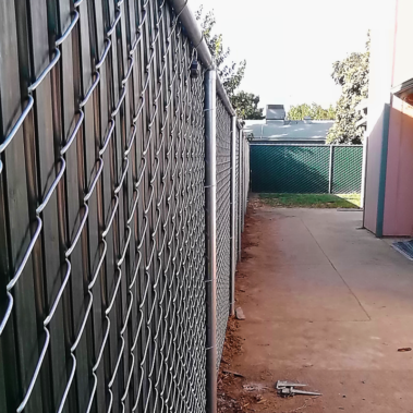 In the foreground, a chain link fence is visible, enclosing the area in front of a building for security purposes.
