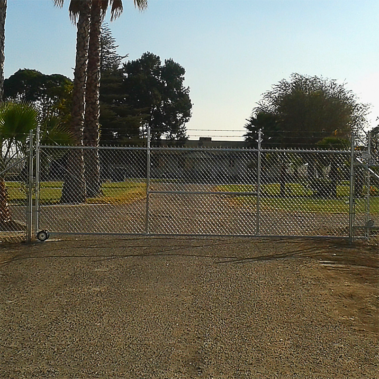 A fence gate leading to a driveway, inviting entry into a private property.