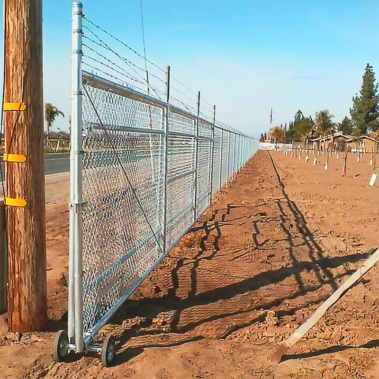 A chain link fence shows a barrier between a highway and one's farm with crops securing them