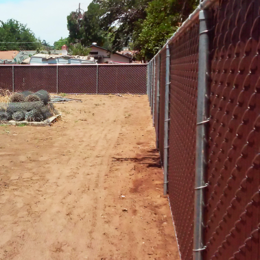 A chain link fence stands prominently in a patch of dirt, showcasing its sturdy structure against the earthy backdrop.