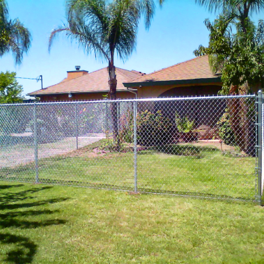 A close-up view of a chain link fence, showcasing its interwoven metal links and sturdy structure against a residential background.