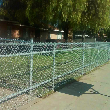 A chain link fence stands in front of a residential house, providing a clear boundary around the property.
