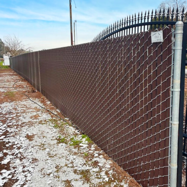 A black gate set within a chain link fence, illustrating a clear division of property or restricted access.