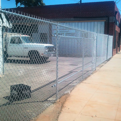 A white truck is parked in front of a chain link fence, showcasing a clear view of the vehicle and its surroundings.